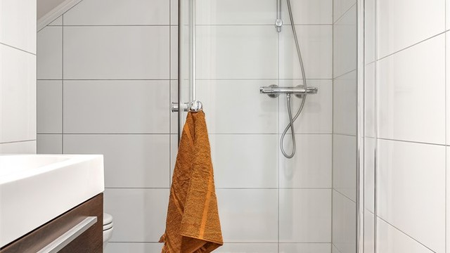 Badet har dusjhjørne med foldedører av glass.