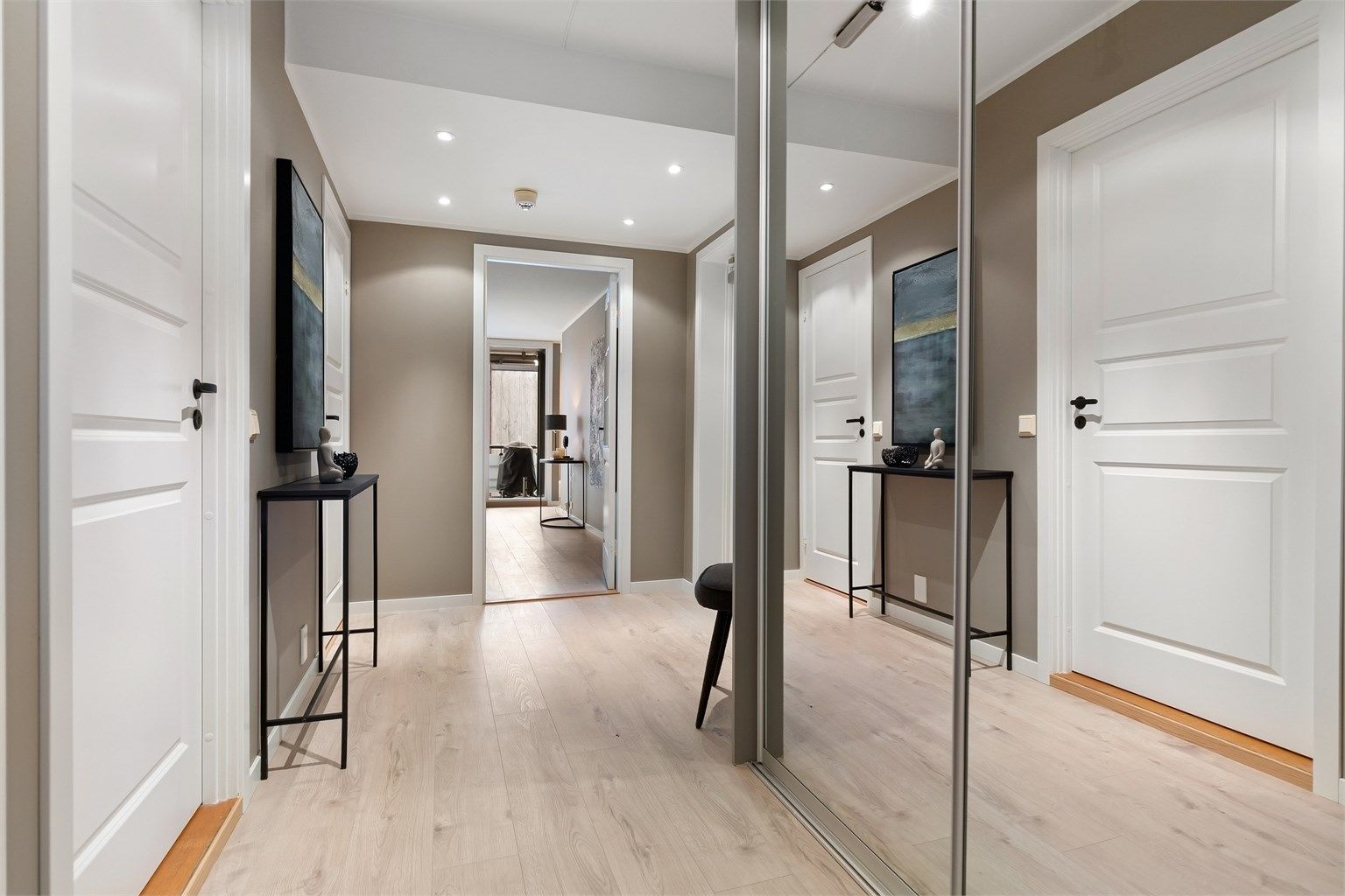 En romslig entré med skyvedørsgarderobe ønsker velkommen. Heis gir adkomst fra garasjeplanet.