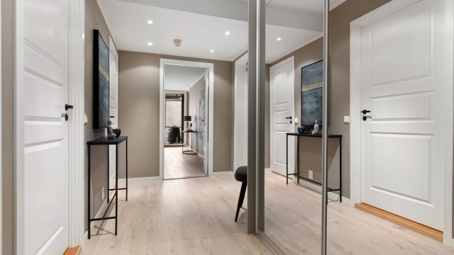 En romslig entré med skyvedørsgarderobe ønsker velkommen. Heis gir adkomst fra garasjeplanet.