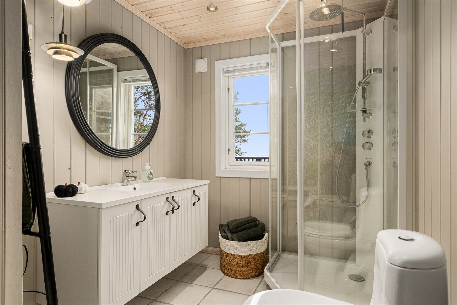 Badet med mulighet for badstue på innsiden ligger i forbindelse med entréen og to av soverommene. Veggene er nylig malt i en lys grå farge og med tapetsert fondvegg på motstående side.