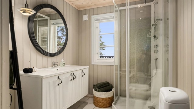 Badet med mulighet for badstue på innsiden ligger i forbindelse med entréen og to av soverommene. Veggene er nylig malt i en lys grå farge og med tapetsert fondvegg på motstående side.