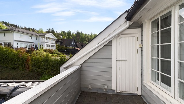 Terrassen har flislagt gulv og rekkverk av tre.