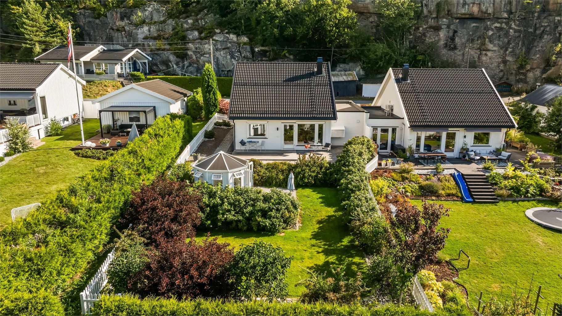 Tomten er nøye planlagt og profesjonelt opparbeidet av hagedesigner og anleggsgartnerfirma. Resultatet er et gjennomført og helhetlig uteområde med flere soner som inviterer til både avslapning, lek og sosiale sammenkomster – i vakre, solrike omgivelser.