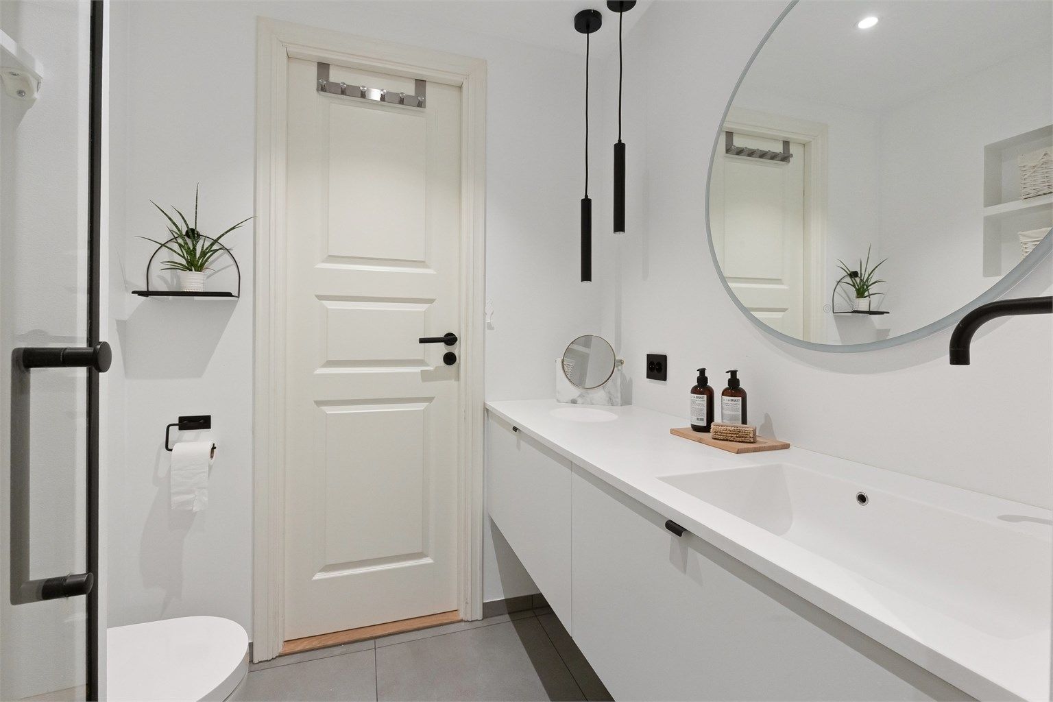 Lekkert baderom fra 2020 med gulvvarme og downlights. Det runde speilet har innebygd belysning. Godt med oppbevaring i benkeskap og integrerte hyllesystemer