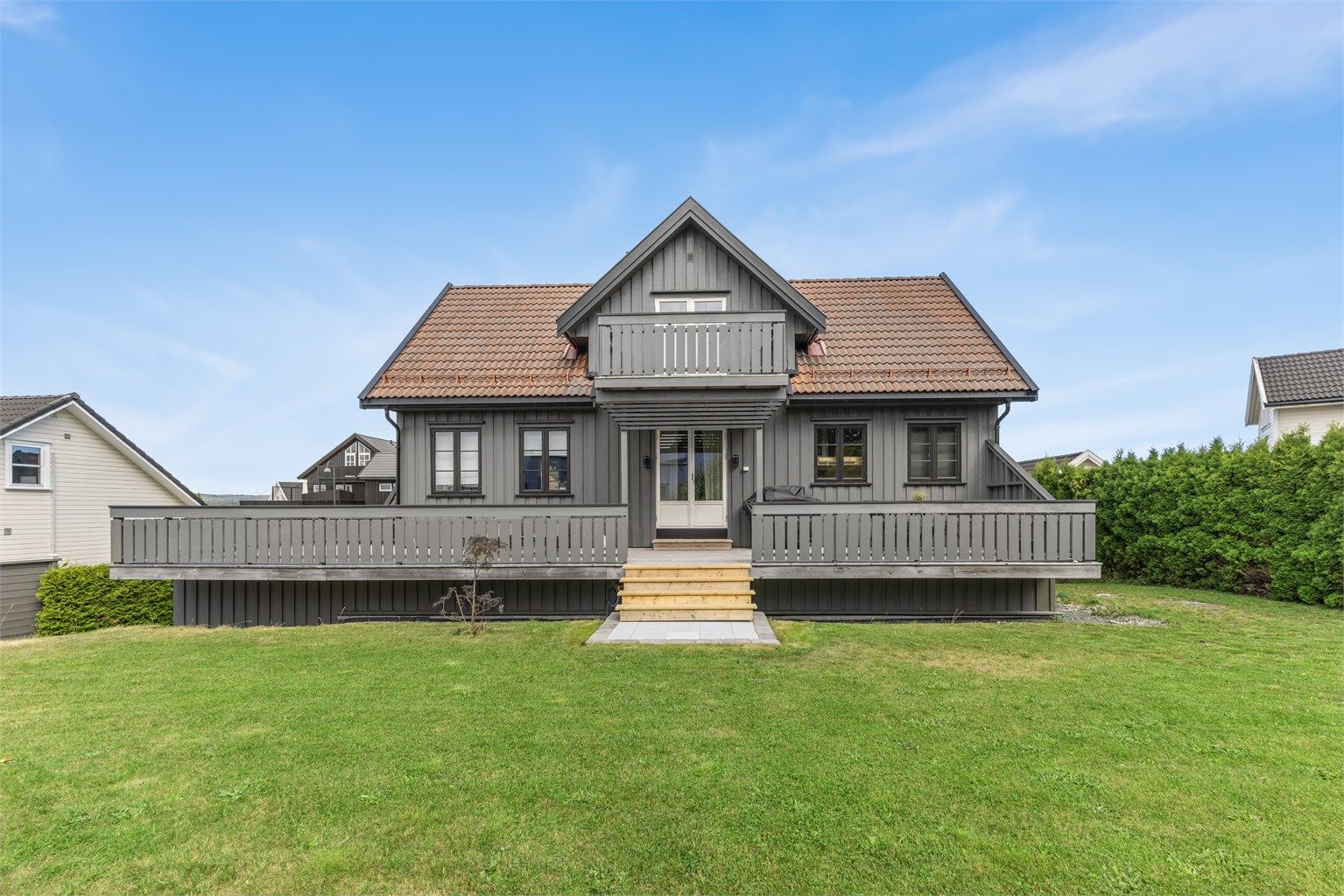 Fin uteplass med veranda og plen på fremsiden av boligen