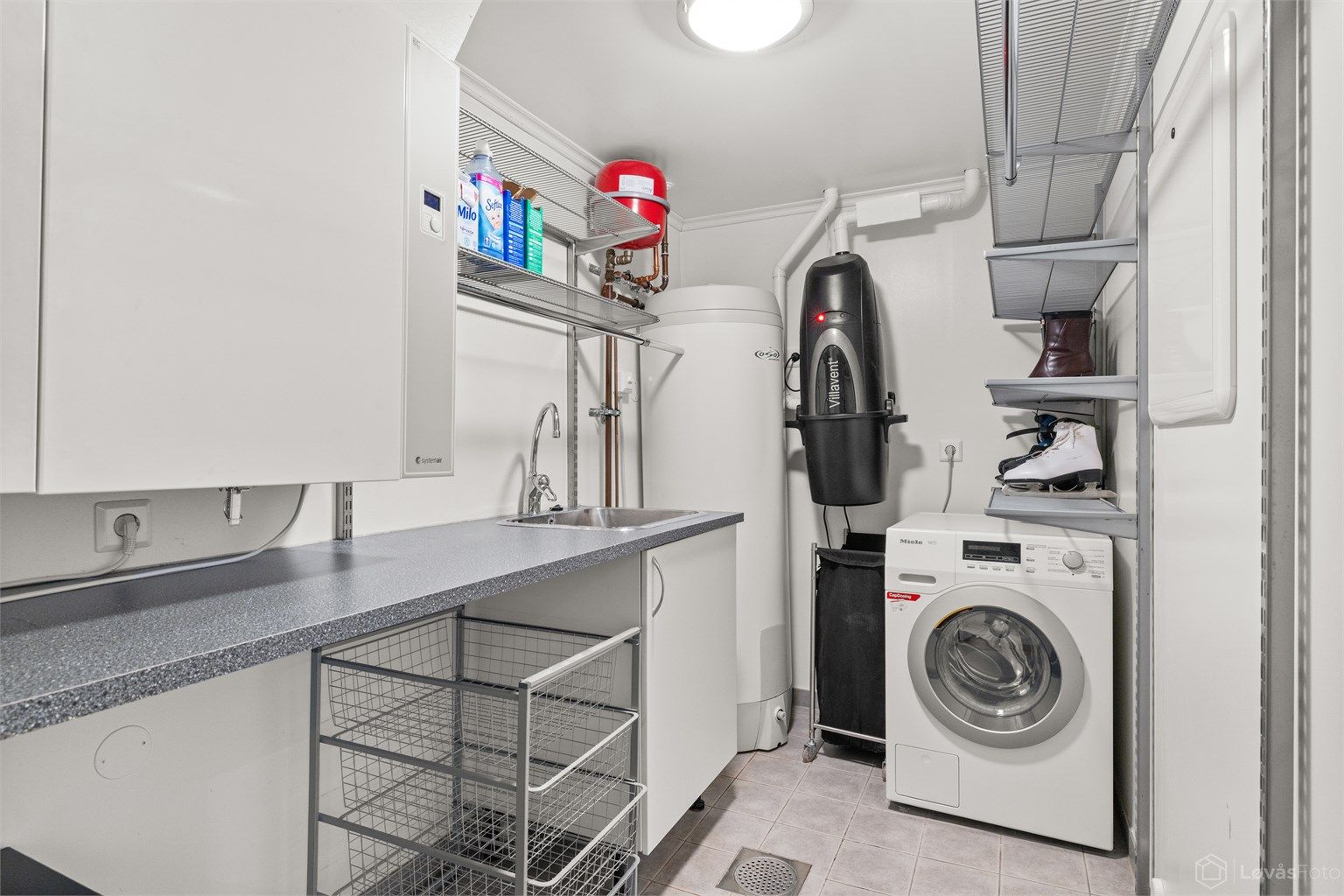 Praktisk vaskerom med flislagt gulv med gulvvarme. Boligens tekniske installasjoner er samlet her, inkludert bl.a. aggregat for balansert ventilasjon og sentralstøvsuger 