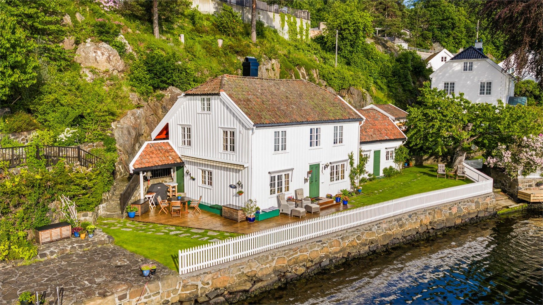 Eiendommen sett fra sjøsiden, med den karakteristiske hvite trebebyggelsen.