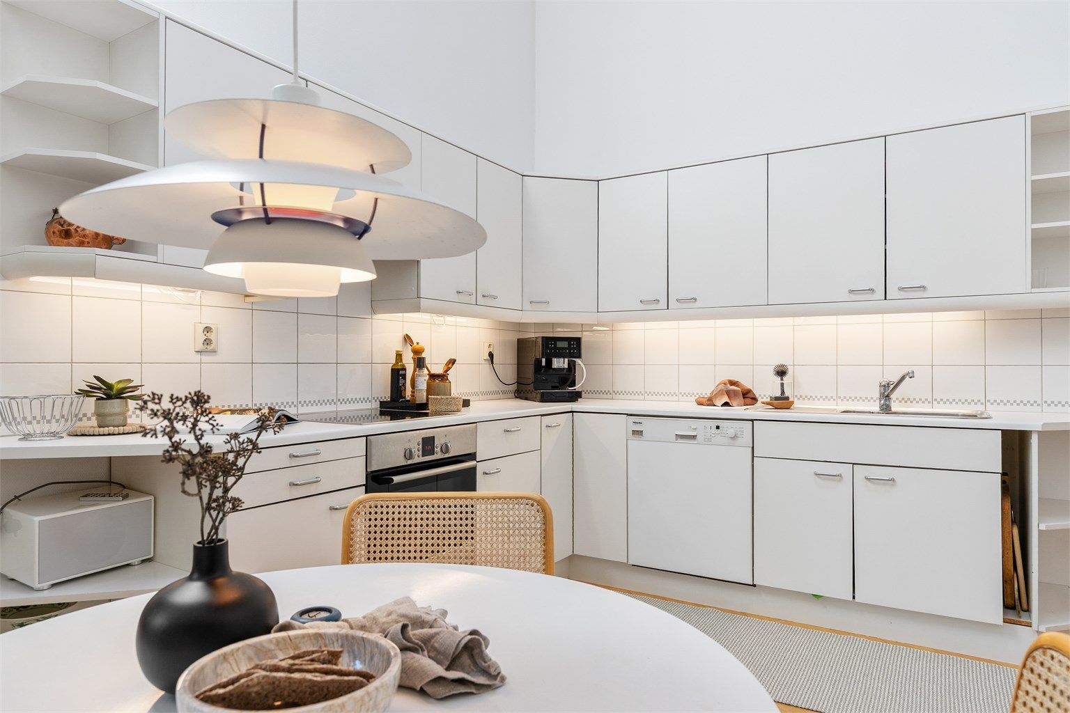 Norema kjøkkeninnredning fra byggeår med glatte fronter og benkeplate med laminert overflate. Kjøkkenvask med armatur og benkeskapsbelysning og stikkontakter over kjøkkenbenk. Integrert stekeovn og platetopp. 