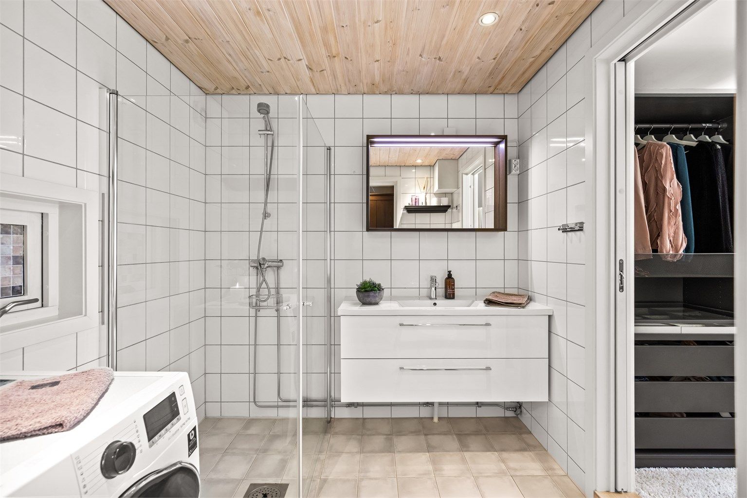 Badet er utstyrt med vegghengt servantinnredning med skuffer og speil med overlys.