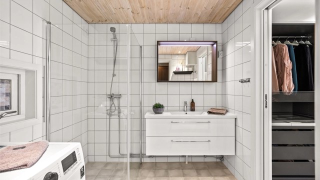 Badet er utstyrt med vegghengt servantinnredning med skuffer og speil med overlys.