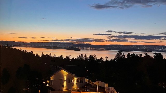 Himmelen fylles av magiske farger som glir over i et hav av bylys fra Oslo, som lyser opp horisonten når kvelden faller på.