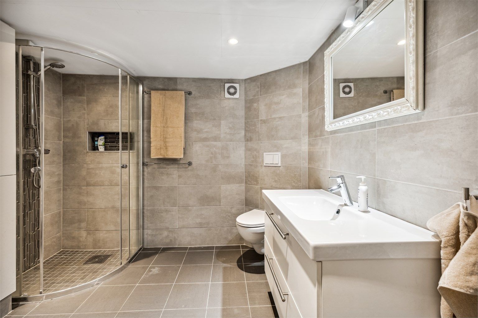 Delikat flislagt bad med diverse oppgraderinger gjort i 2020. Benkeskap og veggskap med glatte fronter, samt dusj med dør i herdet glass (ikke omsøkt/godkjent til varig opphold)