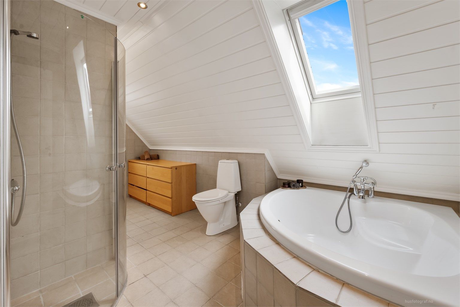 Badet har flislagt gulv med gulvvarme og et takvindu som gir godt med dagslys.