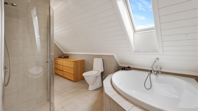 Badet har flislagt gulv med gulvvarme og et takvindu som gir godt med dagslys.