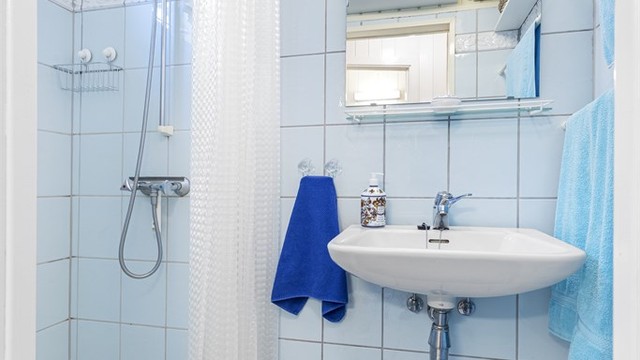 Badet i hovedetasjen har flislagt gulv med varmekabler og fliser i dusjsonen.