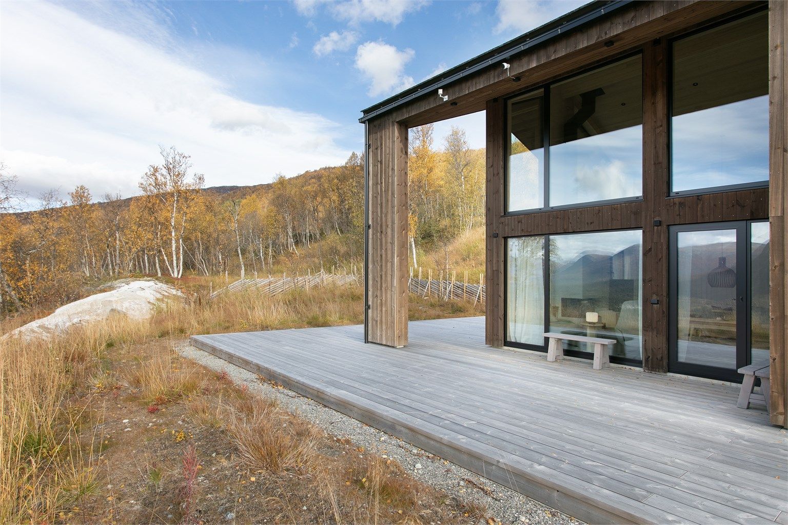 Fasade kledd med stående bordkledning og aluminiumsvinduer med 3-lags glass.