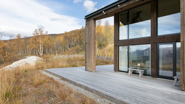 Fasade kledd med stående bordkledning og aluminiumsvinduer med 3-lags glass.