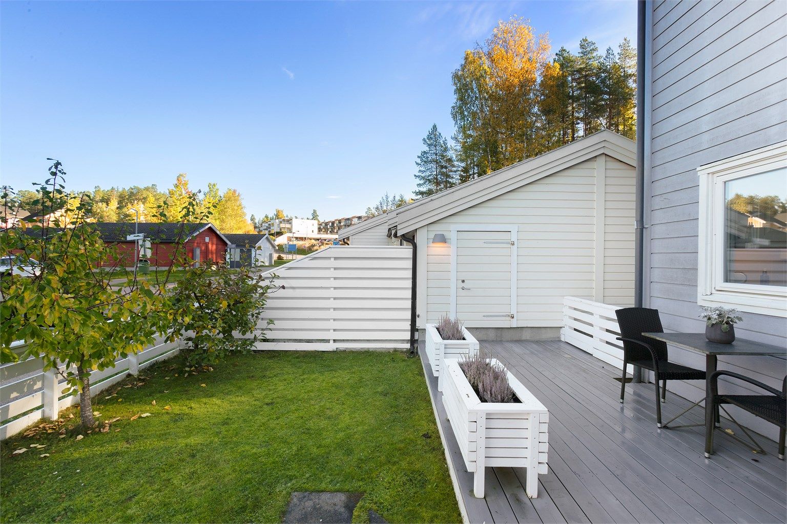 Plen og terrassebord rammet inn av hvitmalt gjerde.
