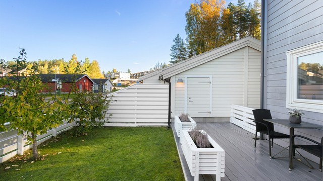 Plen og terrassebord rammet inn av hvitmalt gjerde.