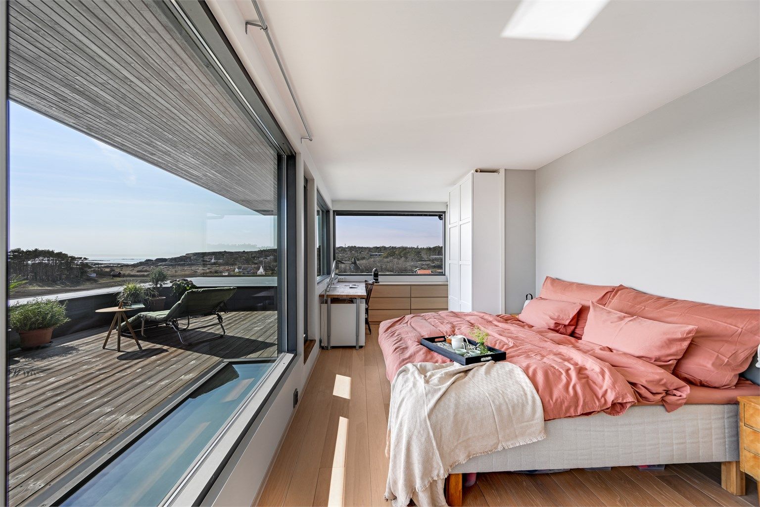 Hovedsuiten i andre etasje har parkettgulv og store vinduer mot havet. Herfra er det direkte utgang til den private, sørvendte takterrassen på 34 m².