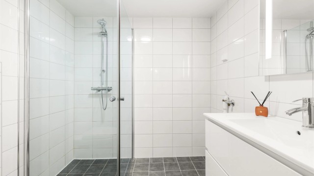 Badet i kjelleren har flislagt gulv med gulvvarme, dusjnisje og vegghengt toalett.