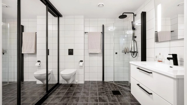 Badet har flislagt gulv med varmekabler, vegghengt toalett og dusj med innfellbare glassdører.