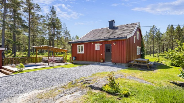 Eneboligen har stående trekledning og tak tekket med Skarpnes takstein i 2017.