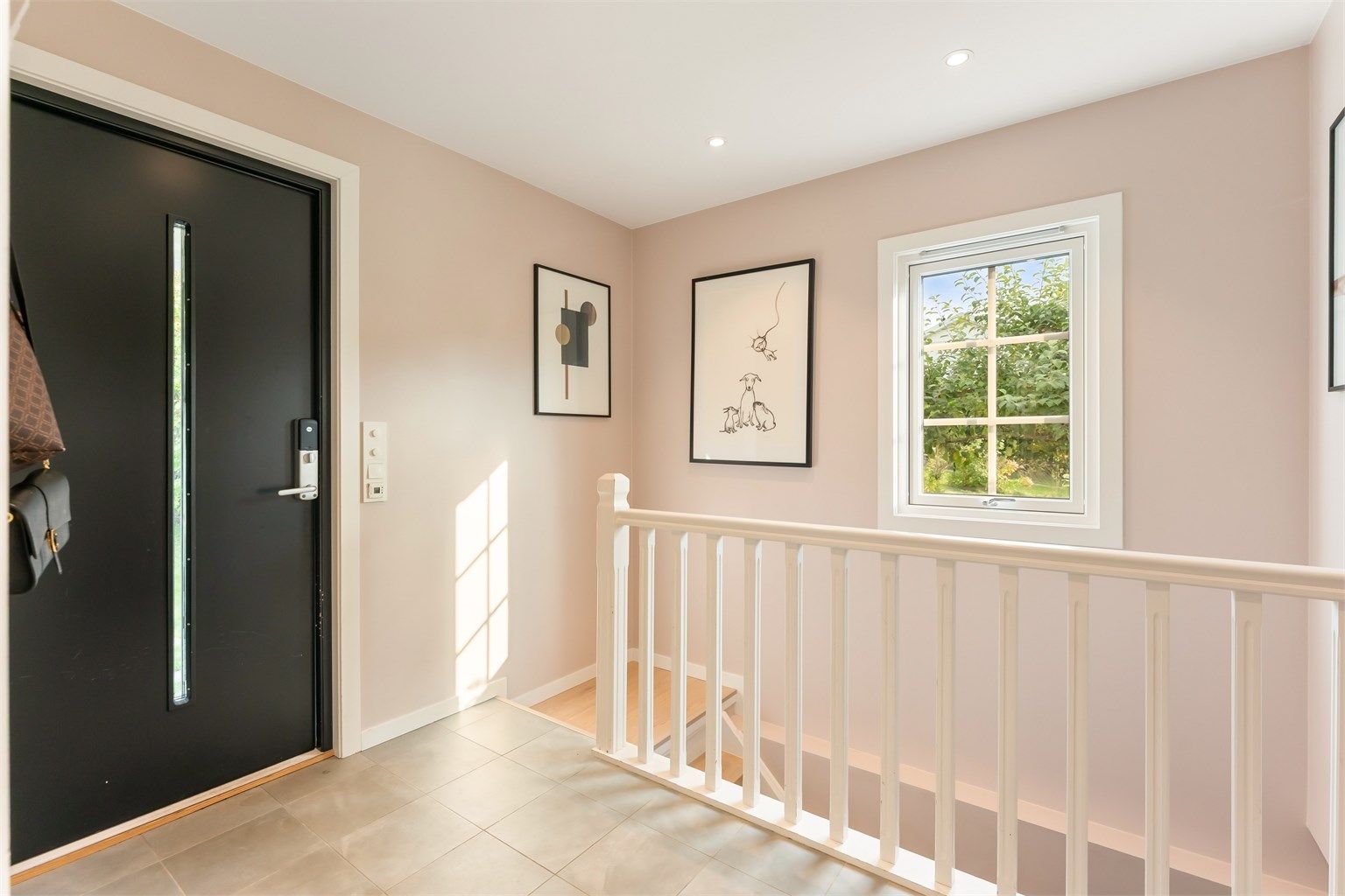 Lys og romslig entrè med flislagt gulv, gulvvarme og downlights i himling
