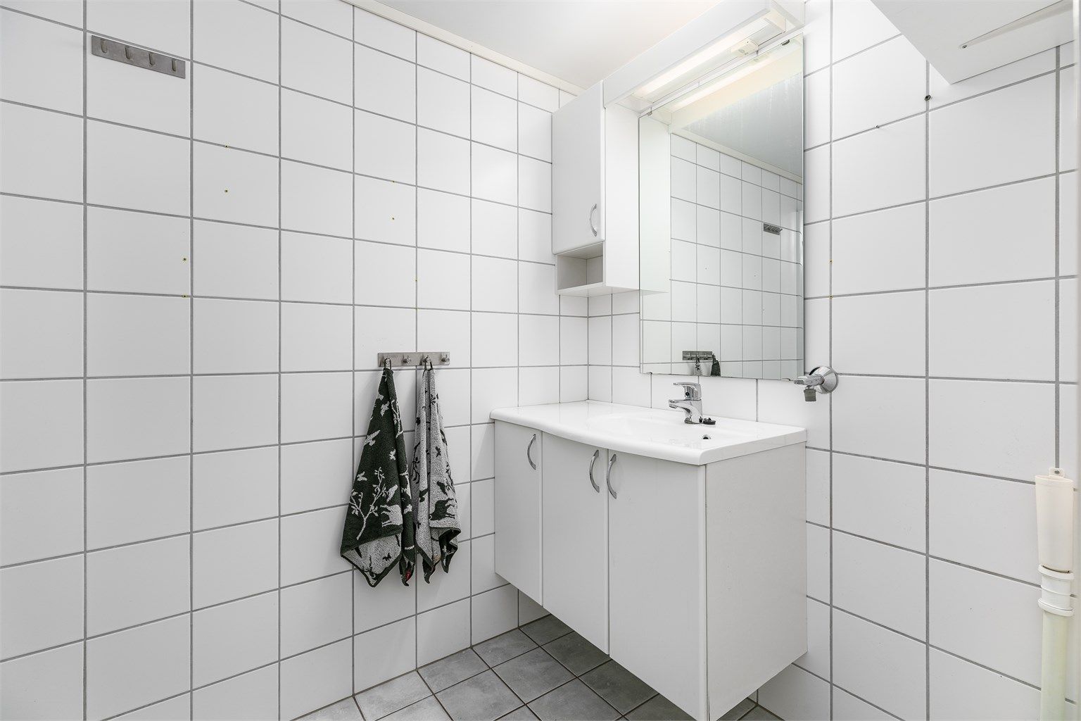Badet er fra leilighetens byggeår og har gulvvarme. Gulvet og veggene er utført med fliser.