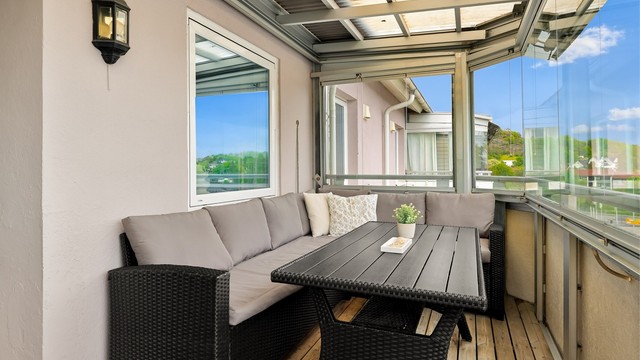 Fra stuen er det utgang til en overbygd og innglasset balkong på 10 kvm. Balkongen er belagt med terrassebord og har rekkverk i glass og metall. Det er montert utebelysning.