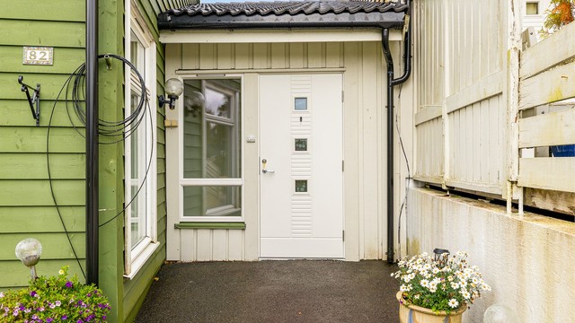 Skjermet inngangsparti med hvit ytterdør og glassfelt.