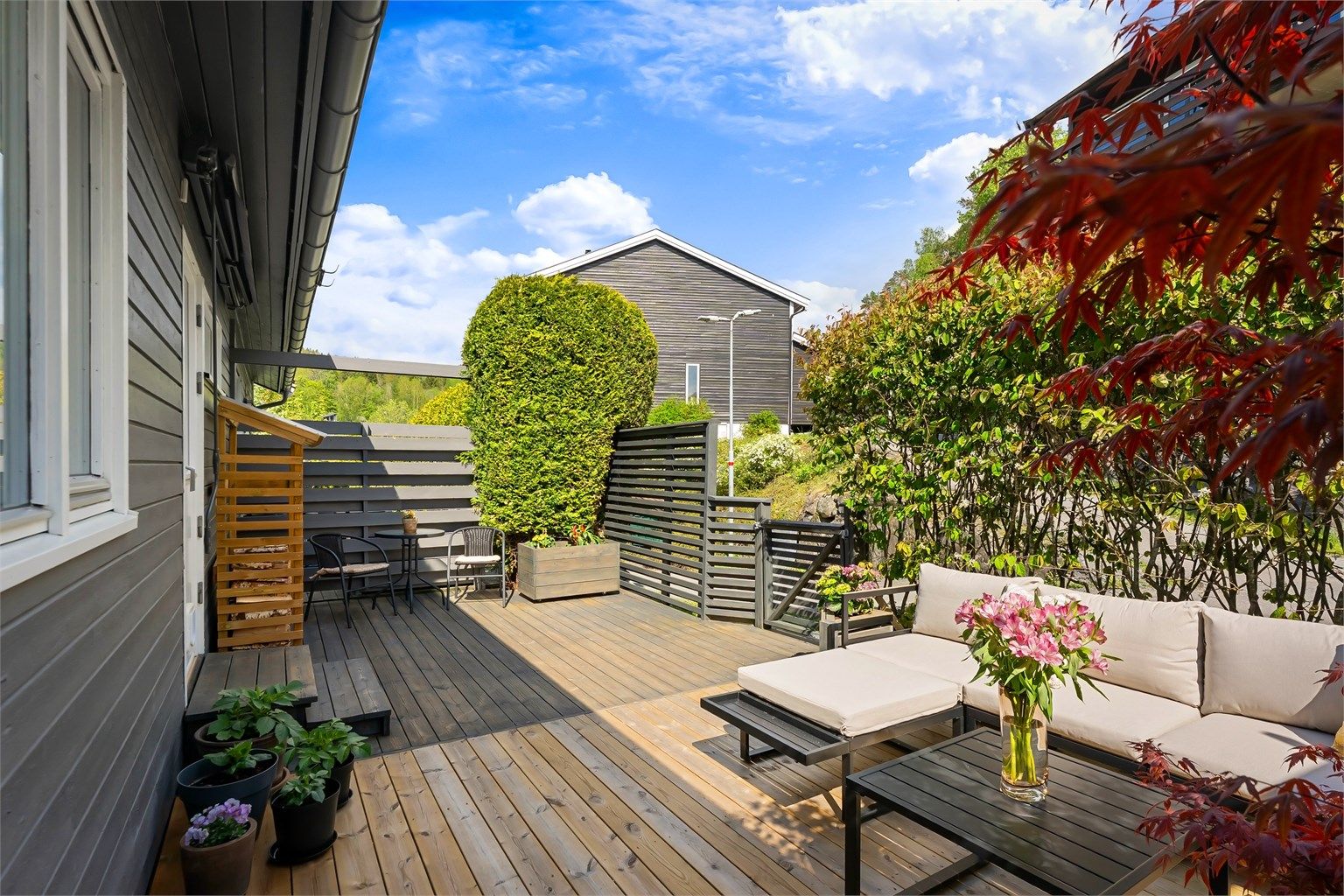 Terrassen er bygget i trekonstruksjoner og er pent rammet inn av beplantning.