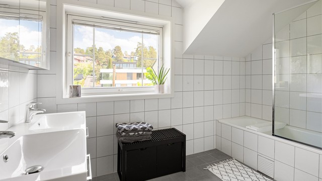Badet er utstyrt med både badekar og dusjhjørne, samt en innredning med doble servanter.