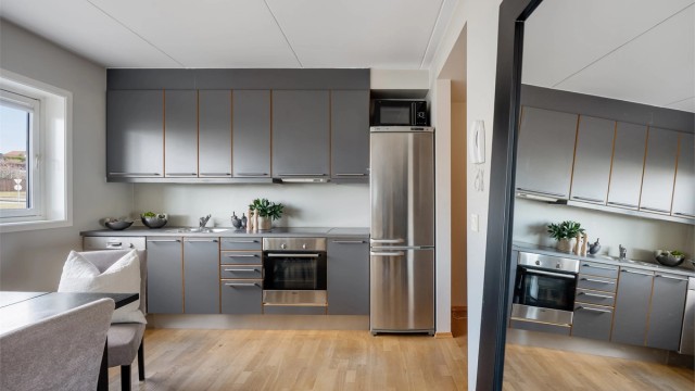 Kjøkkenet er i moderne og fint design med grå fronter og mørk benkeplate.