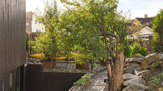 Skjermet gangsti i hagen med natursteinsmurer og beplantning. Hybeldel har eget skjermet uteareal adskilt fra hoveddel.