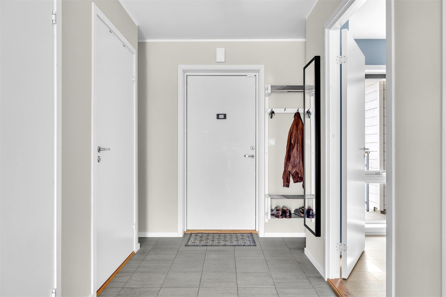 Romslig entrè med flislagt gulv og varmekabler