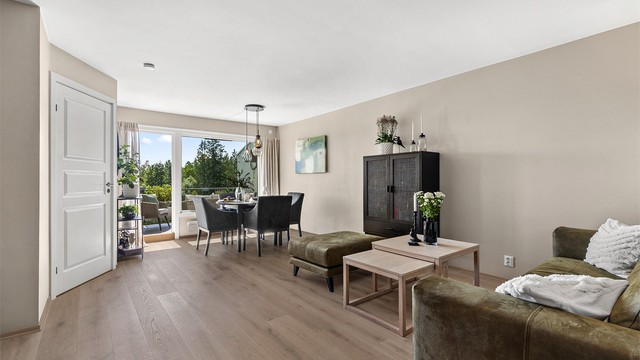 Romslig stue med plass til sittegrupper, TV-område og spisebord.