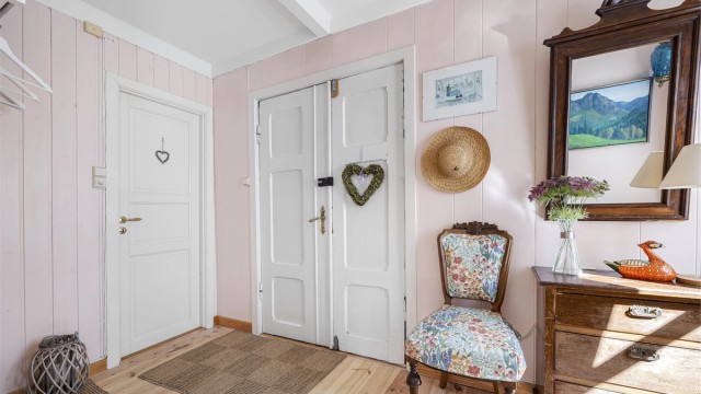 Entréen ønsker velkommen med tregulv og en sjarmerende, tofløyet inngangsdør i tre.