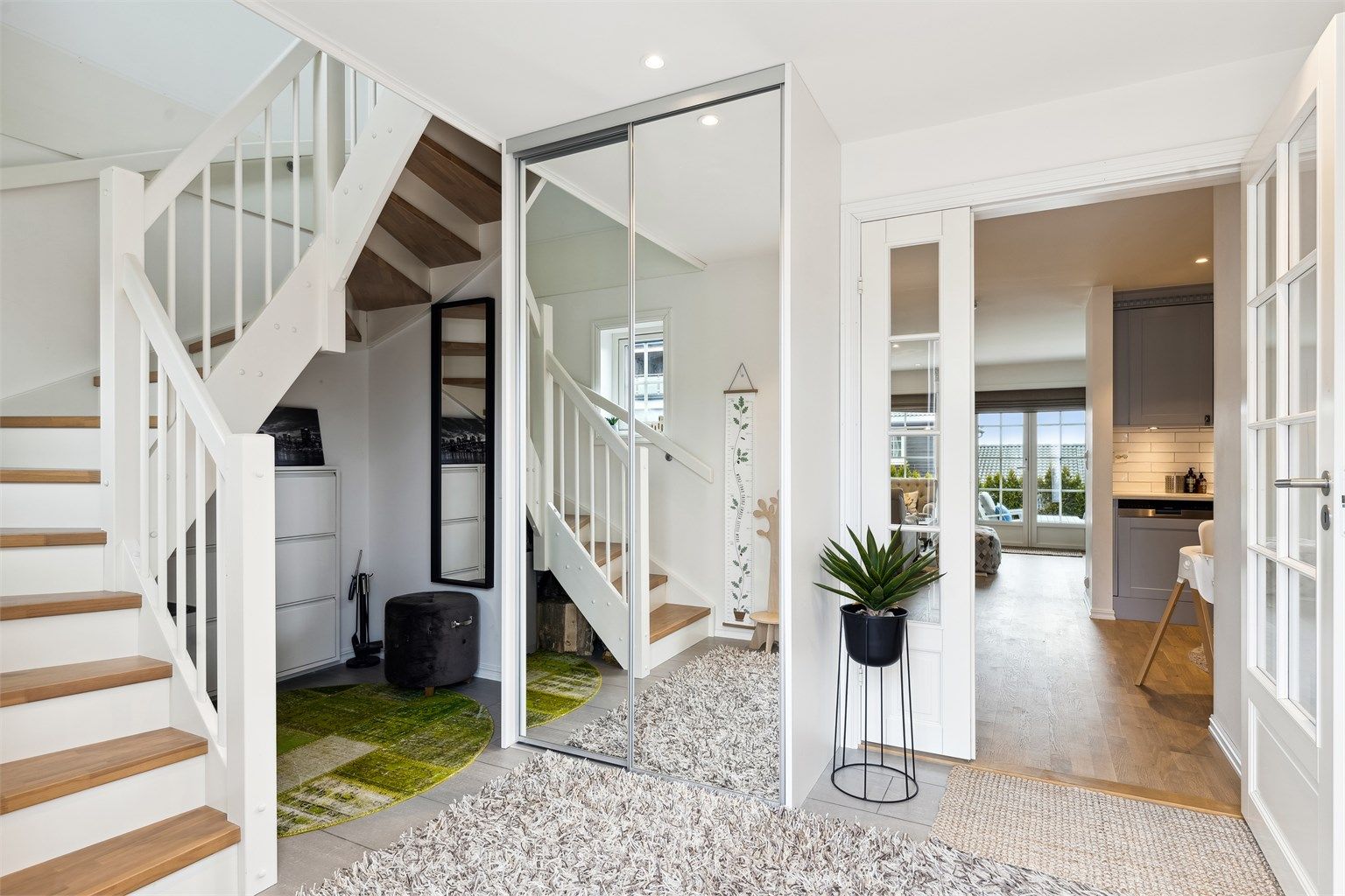 Velkommen inn i en flislagt entré med skyvedørsgarderobe