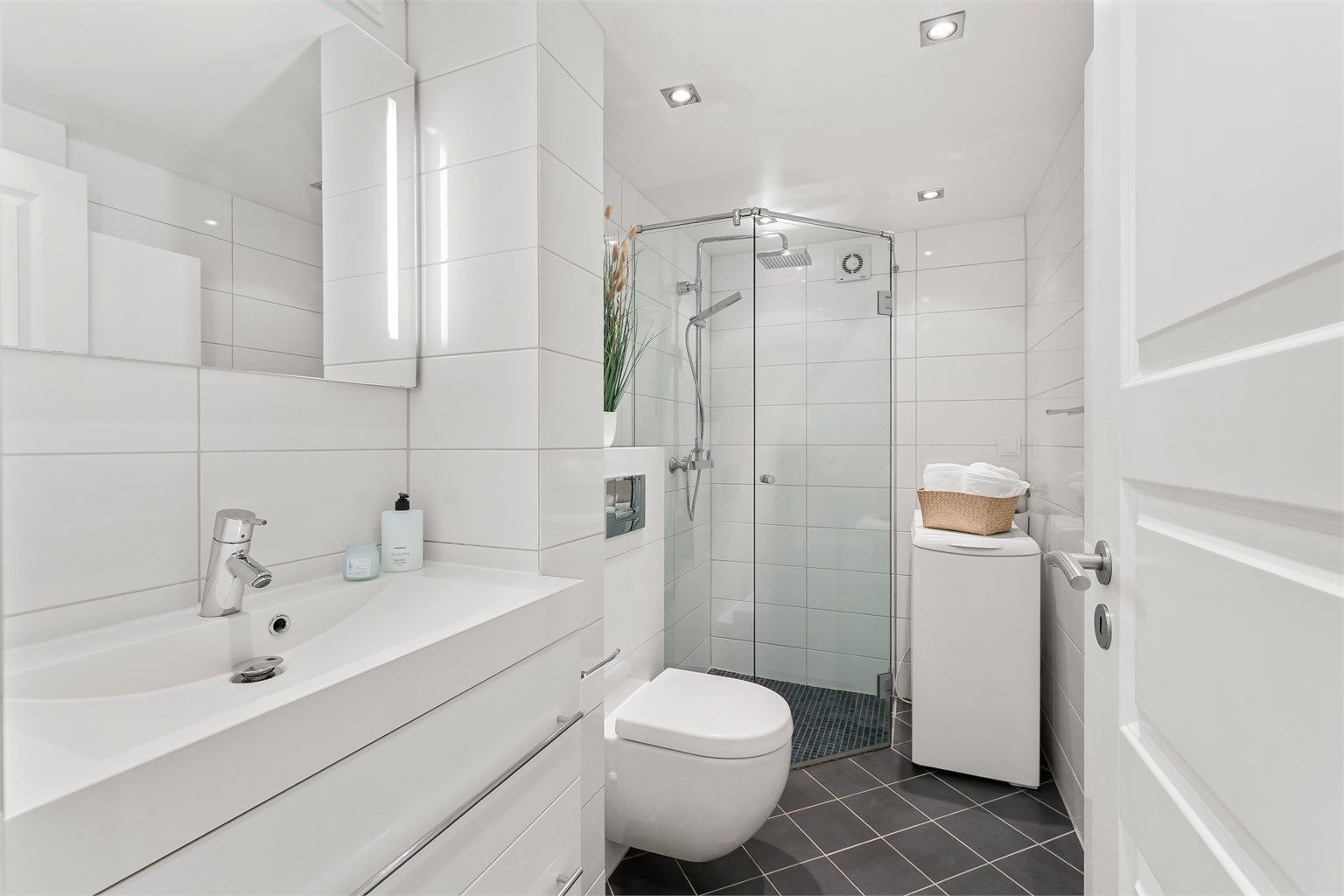 Her er det flislagt gulv med varmekabler, downlights i taket og opplegg for vaskemaskin.