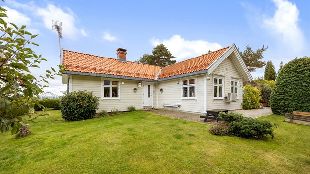 Eneboligen ligger skjermet til med lettstelt plen og belegningsstein.