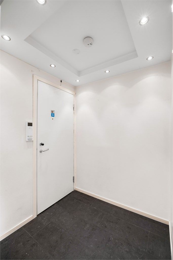 Man kommer inn i en flislagt entré med downlights i tak