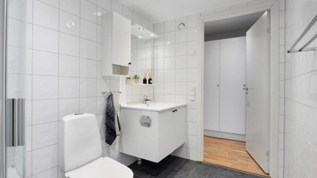 Lyst og pent bad, med flislagt gulv, gulvvarme og flislagte vegger.