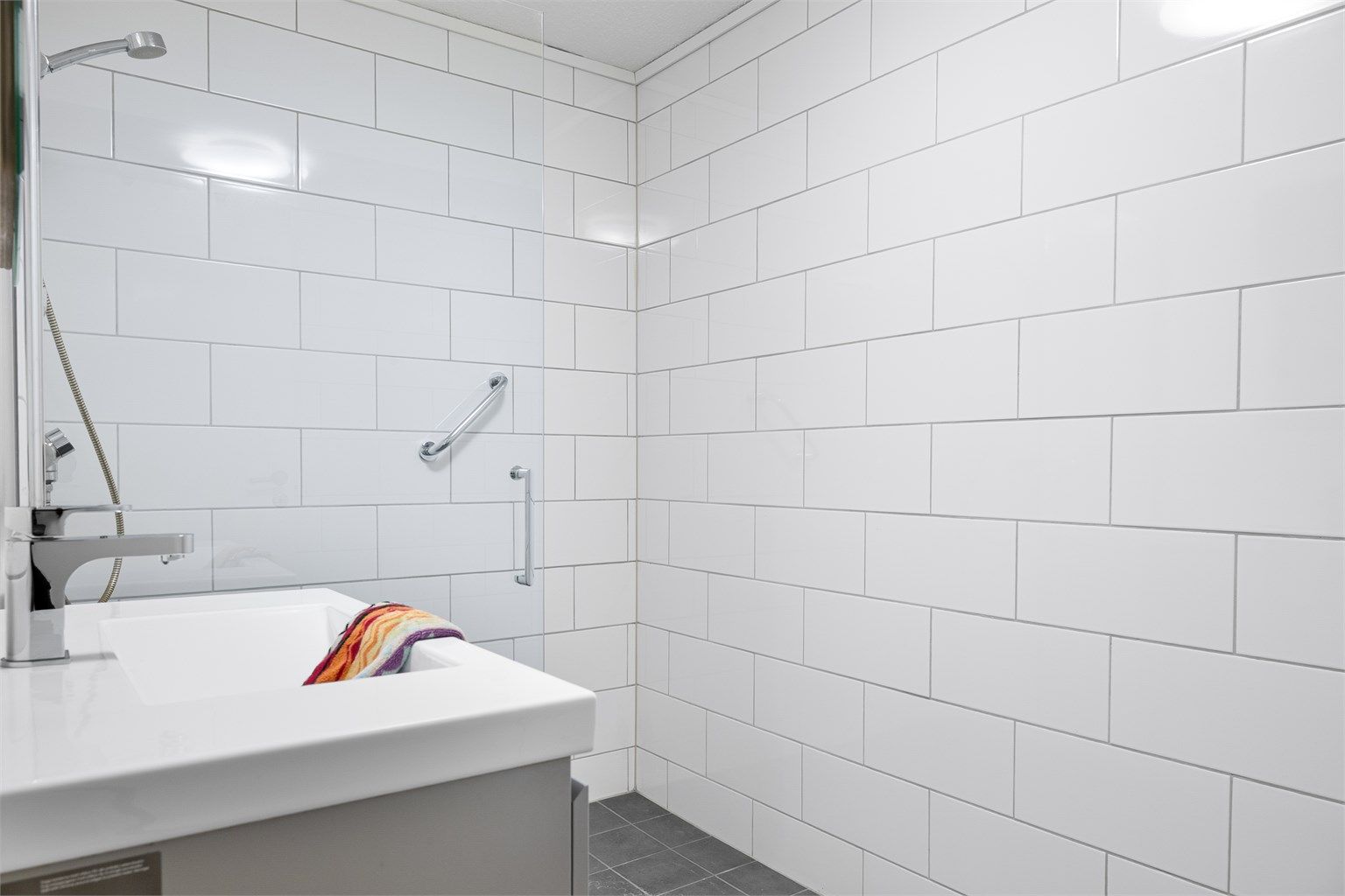 Her er det en romslig dusjnisje med glassvegg og en moderne baderomsinnredning