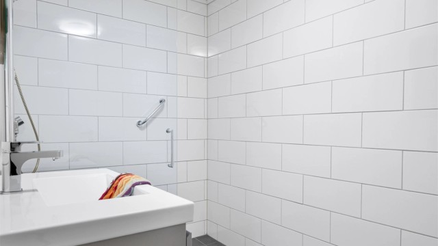 Her er det en romslig dusjnisje med glassvegg og en moderne baderomsinnredning