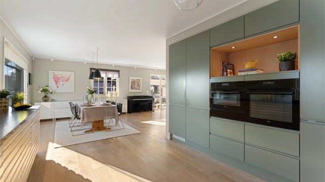 Kjøkkenet er utstyrt med integrerte hvitevarer som kjøleskap, fryseskap, komfyr, mikroovn, oppvaskmaskin og nedfelt platetopp