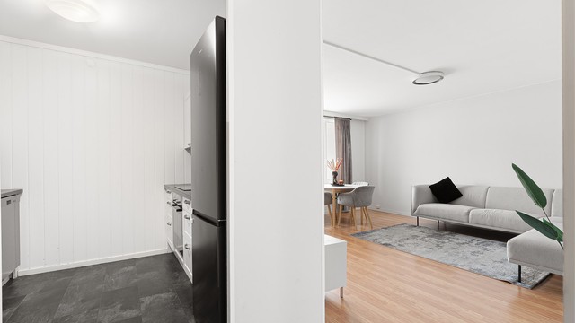 Kjøkkenet ligger naturlig tilbaketrukket fra stuen og er innredet med lyse slette fronter og benkeplate av laminat.