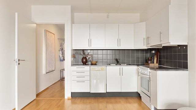 Kjøkkenet er fra byggeår og har tidløse glatte fronter, praktisk laminatbenkeplate og integrert ventilator i overskap.