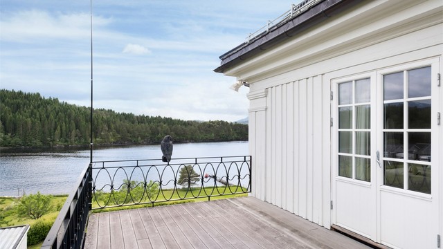 En tofløyet balkongdør i tre med 2-lags isolerglass åpner opp mot terrassen fra hovedsoverommet