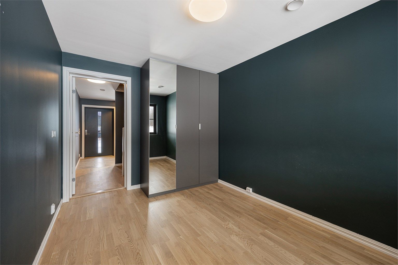 Et stort garderobeskap med speilfronter gir rikelig med oppbevaringsplass.